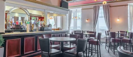 A bar area with a counter, bar stools, and a television mounted above.