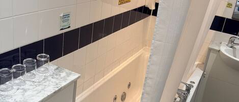 Un baño con bañera, lavabo y espejo.