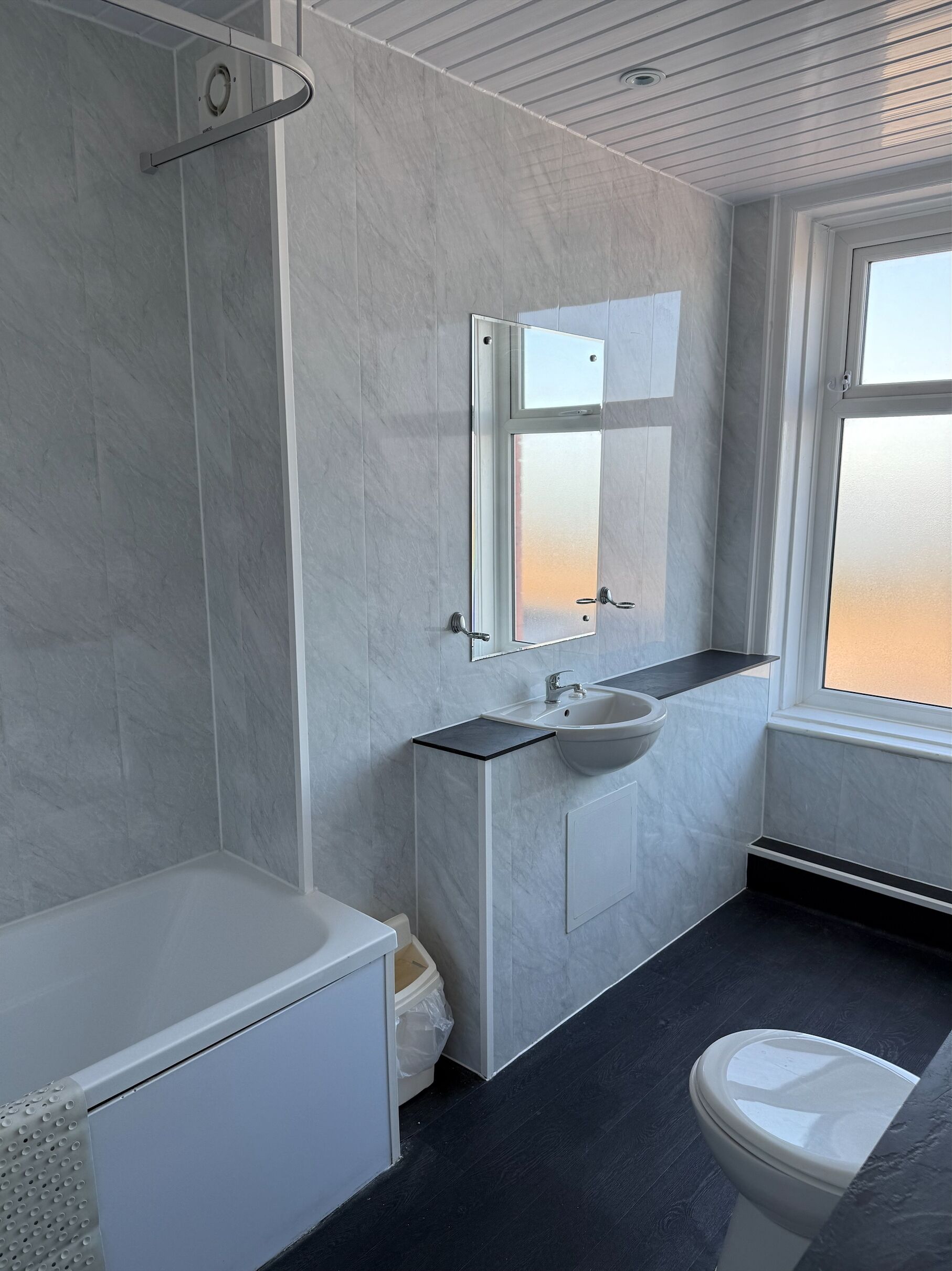 Een moderne badkamer met een bad, wastafel en toilet.