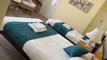 Habitación de hotel con cama, una silla, un escritorio y una puerta.