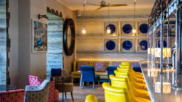 A bar area with yellow chairs, a wooden wall with blue decorative elements, and a ceiling fan.