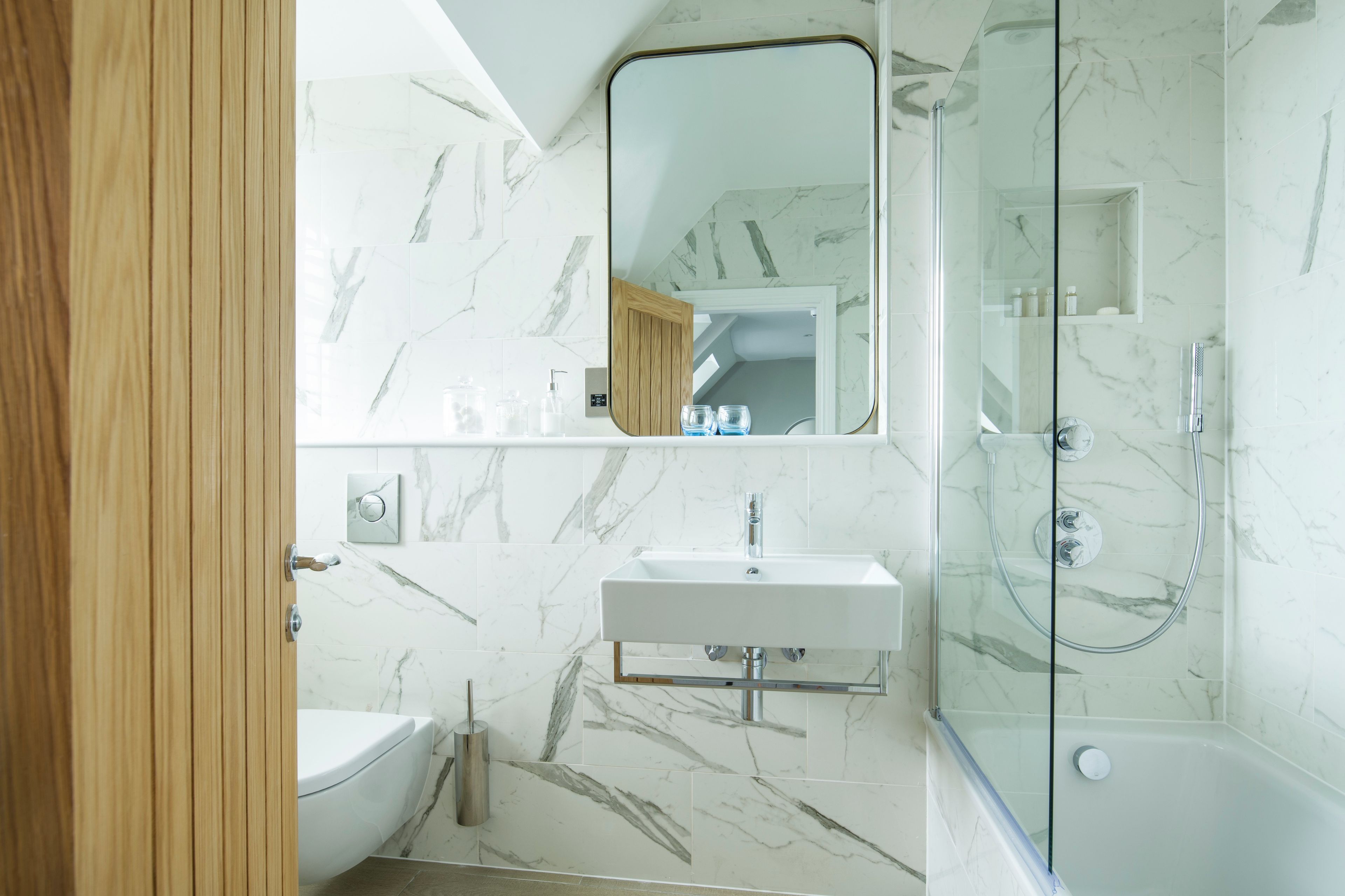 A modern bathroom with a glass-enclosed shower, a white sink, and a toilet.