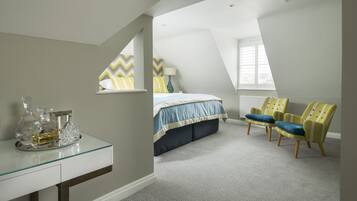 A bedroom with a bed, two chairs, a glass table with bottles, and a window.