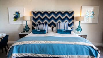 Quarto de hotel bem arrumado com uma cama grande, duas mesas de cabeceira, uma cadeira e obras de arte nas paredes.