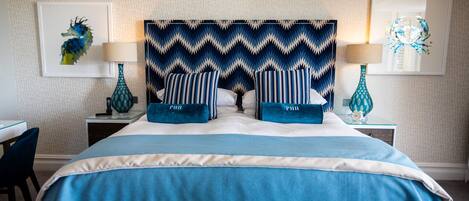 A neatly arranged hotel room with a large bed, two bedside tables, a chair, and artwork on the walls.