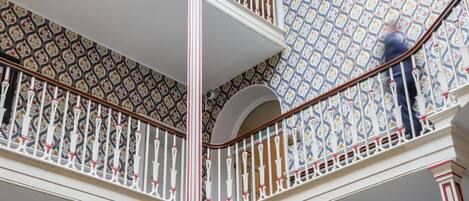 Un intérieur à plusieurs niveaux, agrémenté de balustrades décoratives et de papiers peints à motifs.