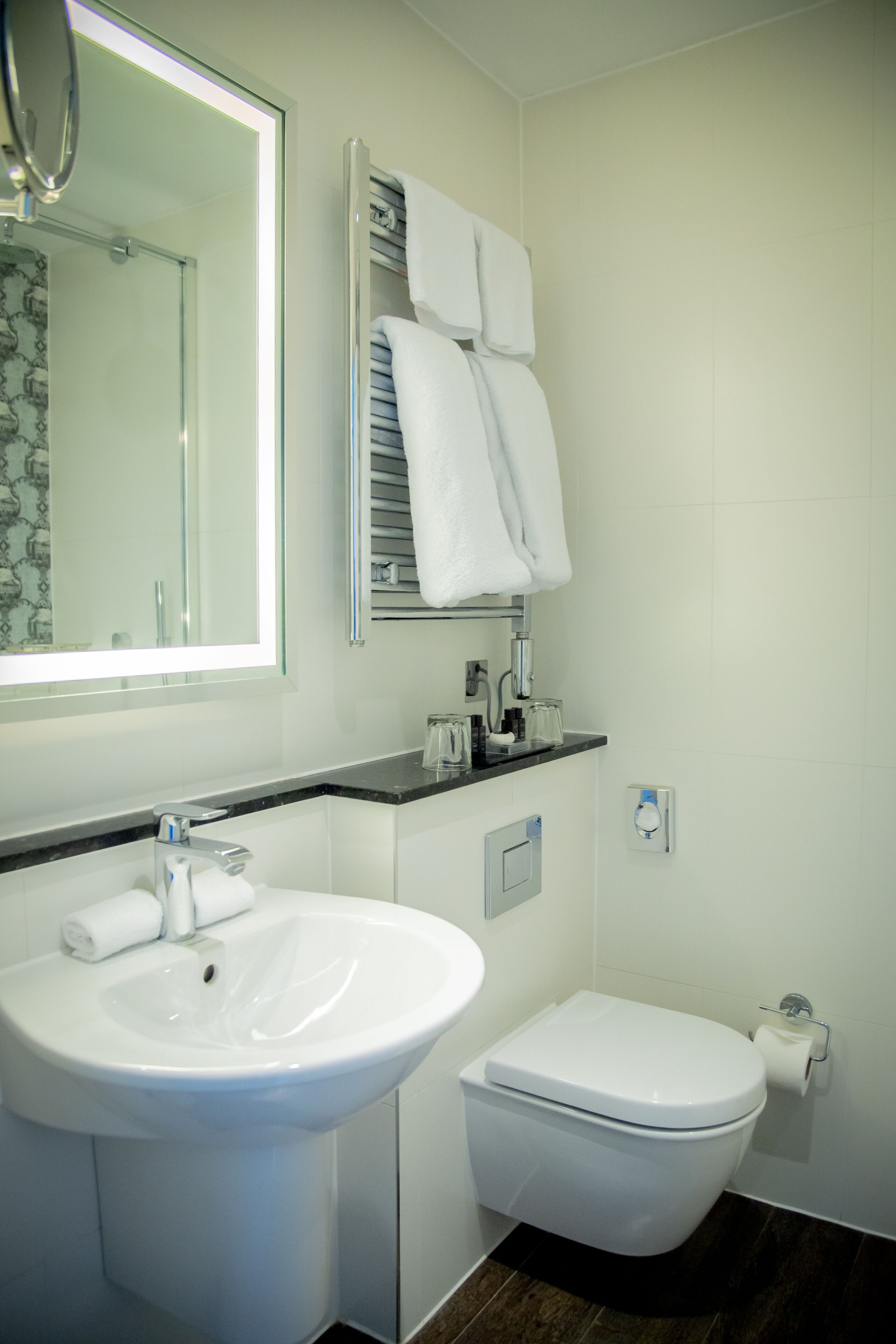 A modern bathroom with a white sink, toilet, and a glass shower enclosure.