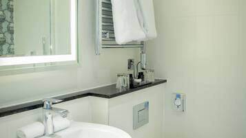 A modern bathroom with a white sink, toilet, and a glass shower enclosure.