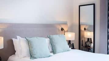 Habitación de hotel con una cama, dos almohadas, una mesita de noche y un espejo.