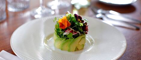 Un plato blanco con ensalada sobre una mesa de madera.