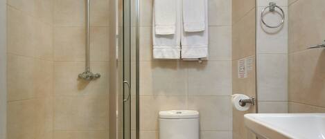 Een moderne badkamer met een douchecabine van glas, een toilet en een wastafel.