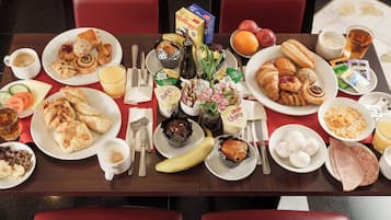 A breakfast buffet with various pastries, fruits, and beverages.