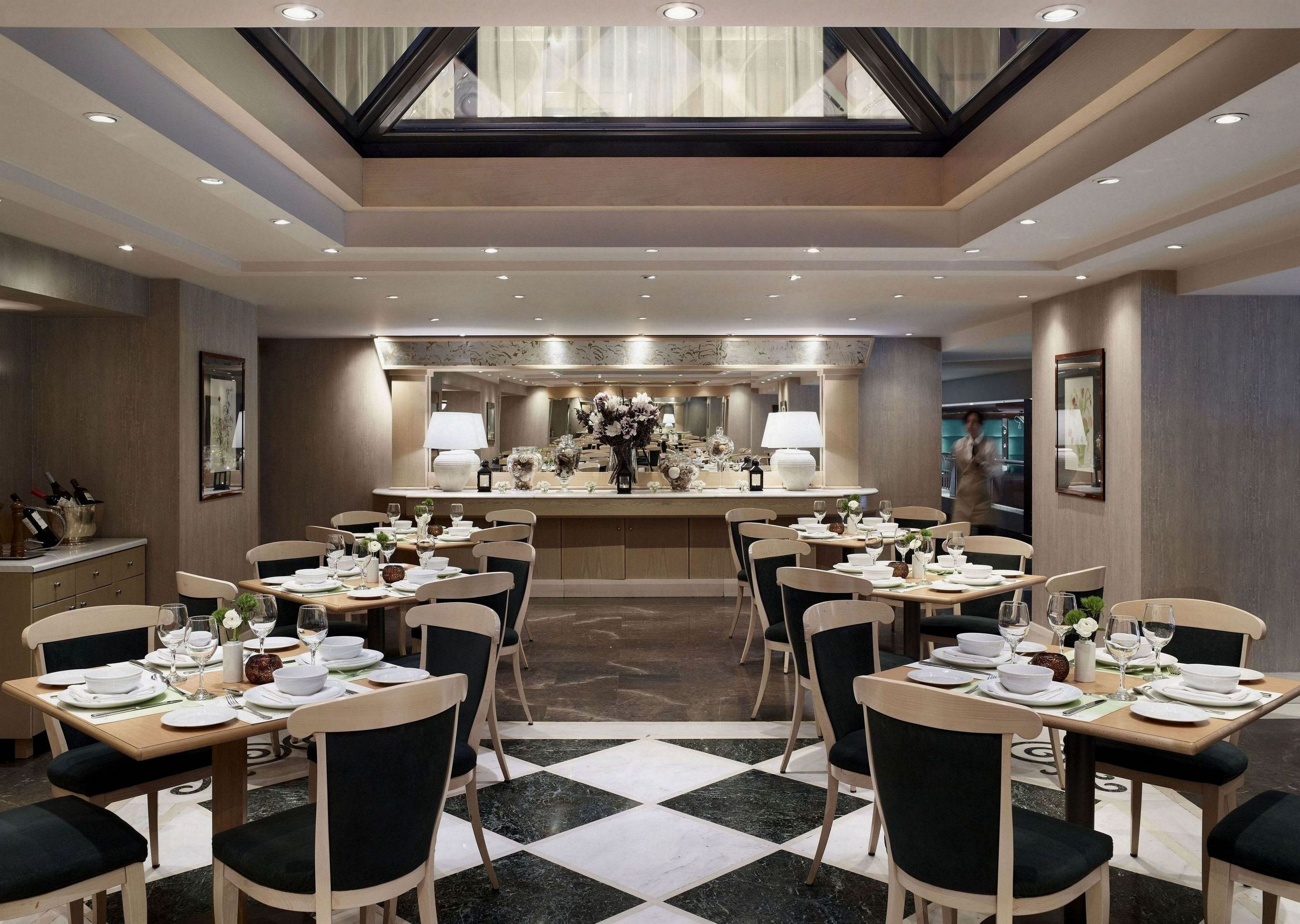 Un espace repas moderne doté d’un îlot central, de plusieurs tables et de chaises.