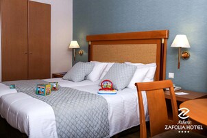 Quarto de hotel com uma cama, duas mesas de cabeceira, um guarda-roupa de madeira e uma pequena mesa com uma cadeira.