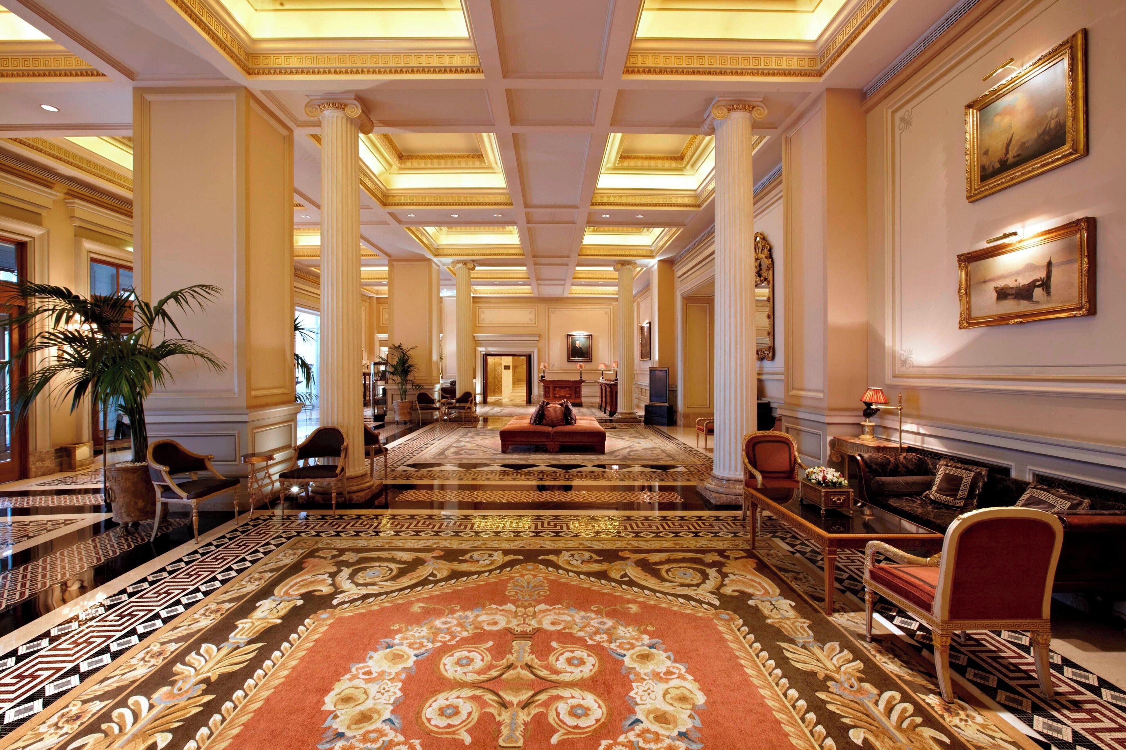 A spacious lobby with a patterned carpet, elegant furniture, and classical architecture.