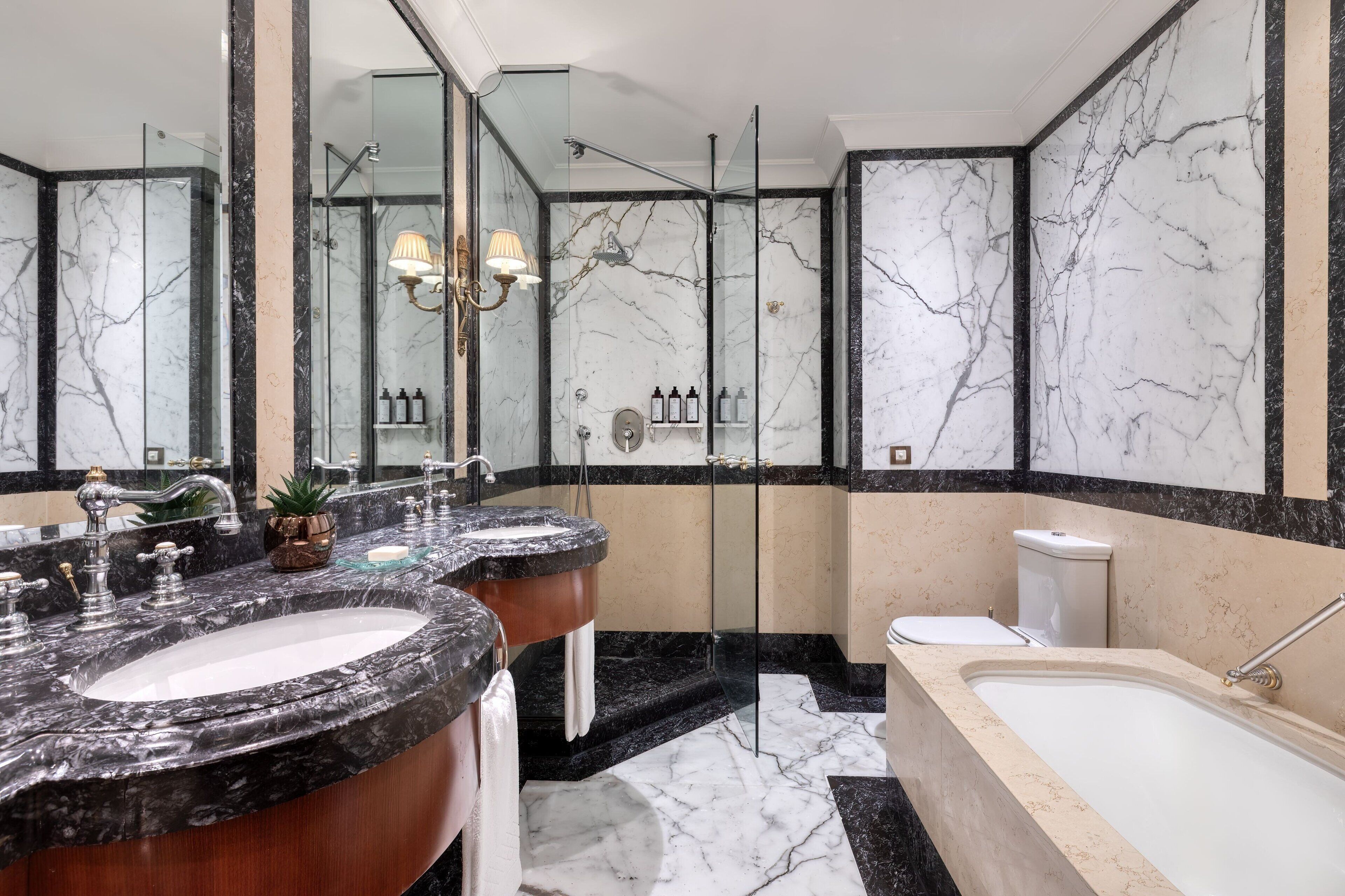 A bathroom with two sinks, a bathtub, and a glass-enclosed shower.
