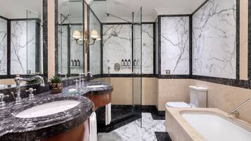 A bathroom with two sinks, a bathtub, and a glass-enclosed shower.