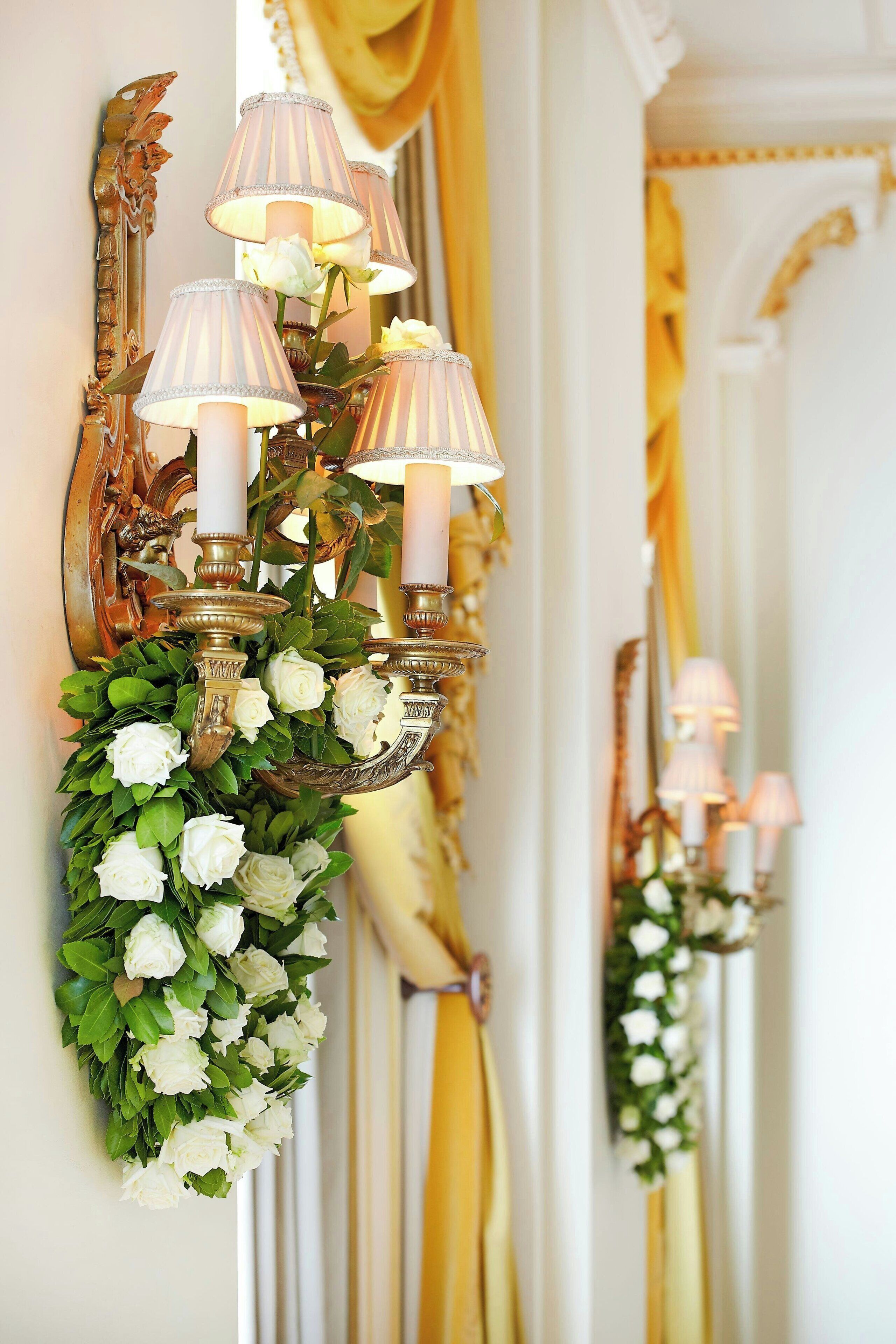 Um candelabro fixado na parede com várias lâmpadas e um arranjo floral.