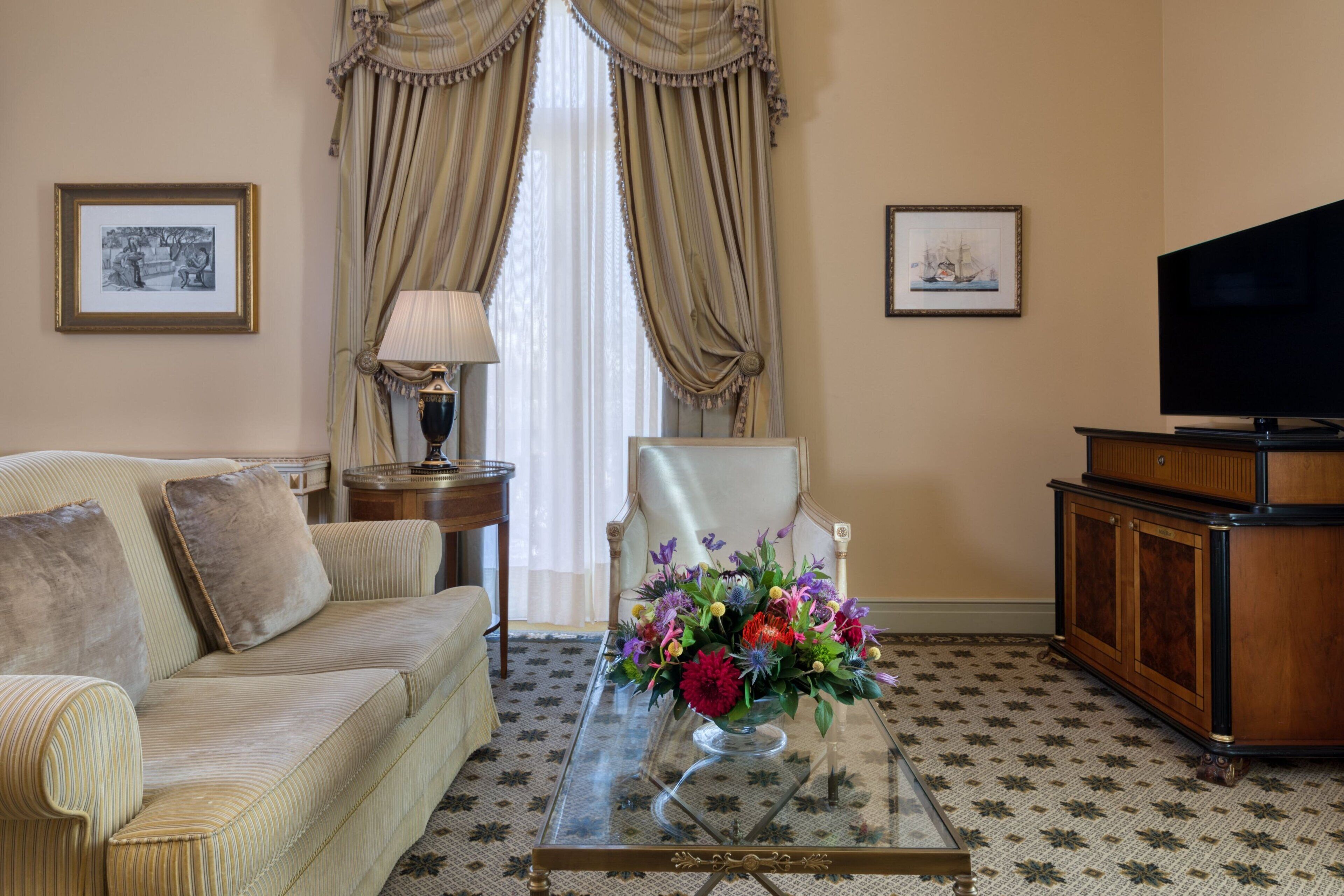 Un salon comprenant un canapé, une table basse en verre agrémentée d’un arrangement floral, un téléviseur et un meuble.