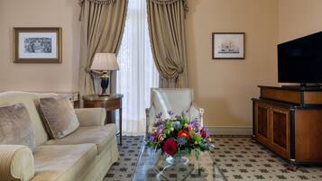 Un salon comprenant un canapé, une table basse en verre agrémentée d’un arrangement floral, un téléviseur et un meuble.