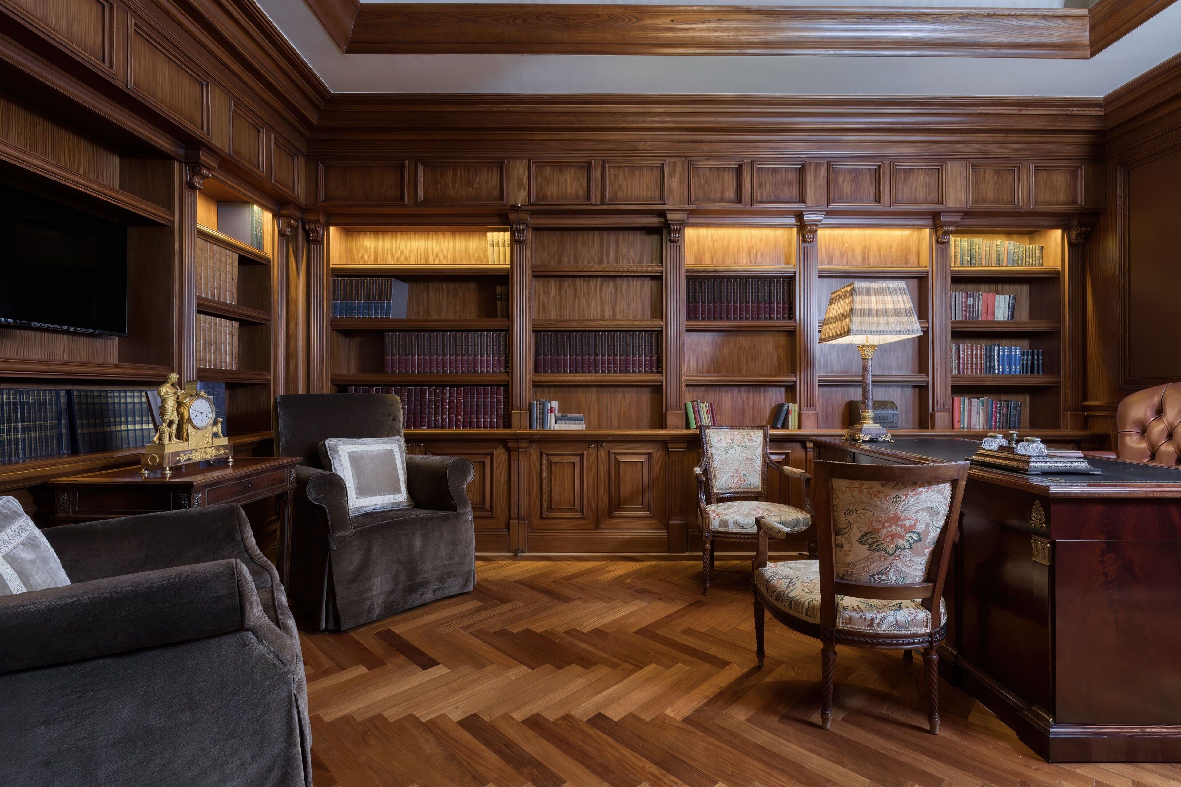 A library with wooden bookshelves, a television, and comfortable seating.