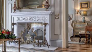 Una habitación lujosa con chimenea blanca, muebles ornamentados y un candelabro clásico.