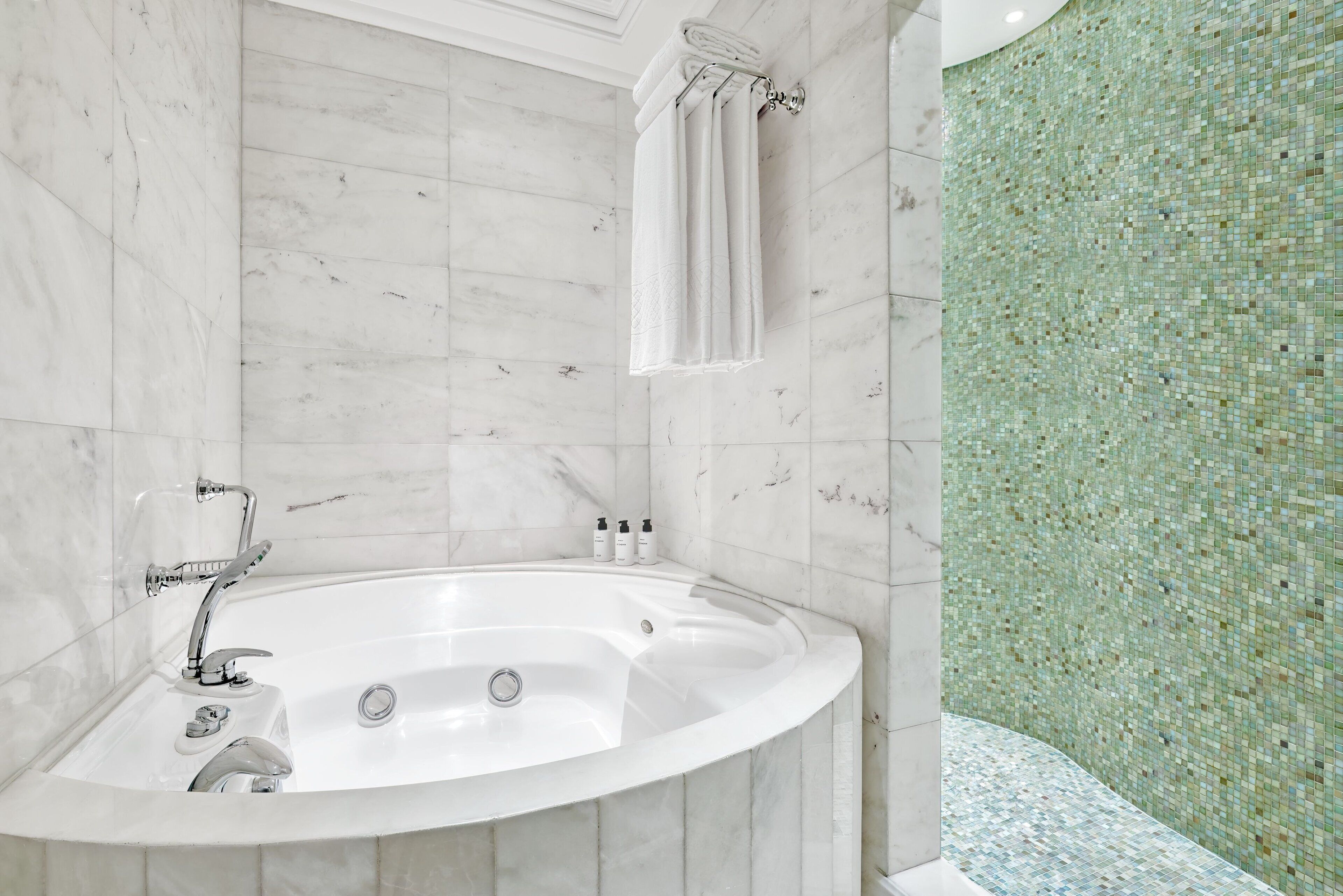 Un baño moderno con una bañera independiente, un perchero y un muro con mosaicos.