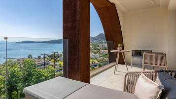 Un balcón con vista al mar, un sofá y una pequeña mesa con sillas.