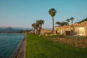 A coastal property with a swimming pool, a well-maintained lawn, and a modern building with large windows.