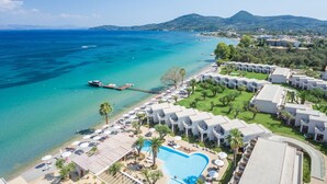 An aerial view of a resort with a pool, beach, and mountain backdrop. - Domes Miramare, a Luxury Collection Resort, Corfu - Adults Only (Corfu)