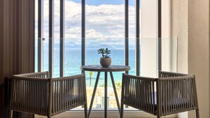 A balcony with two wicker chairs and a small table with a potted plant, overlooking a beach and ocean. - Domes Miramare, a Luxury Collection Resort, Corfu - Adults Only (Corfu)