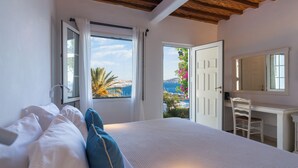 Un dormitorio con cama, escritorio y vista al mar.