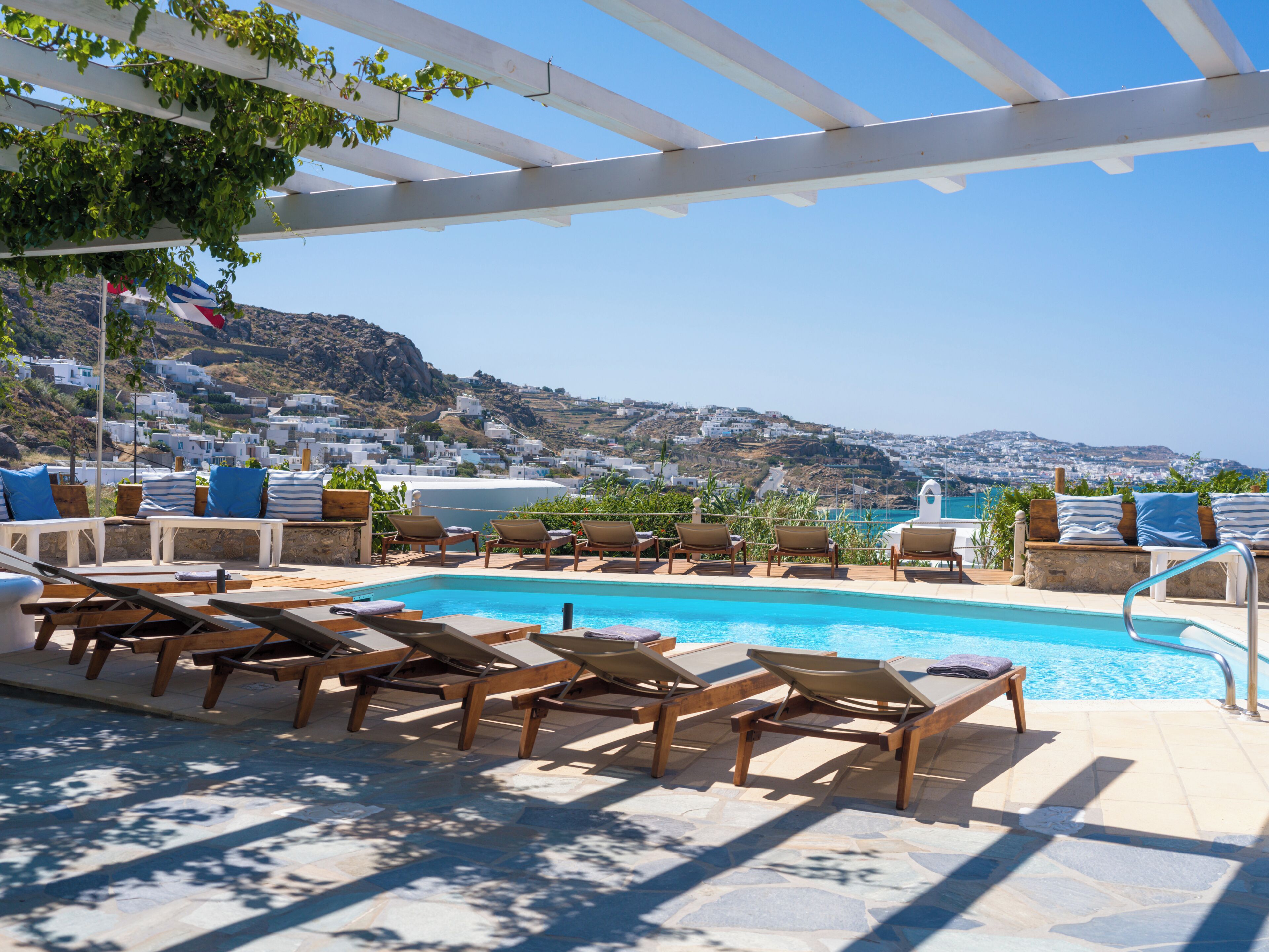A poolside area with lounge chairs and a view of a coastal town.