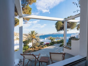 Un balcón con vista al mar, edificios blancos y una palmera.