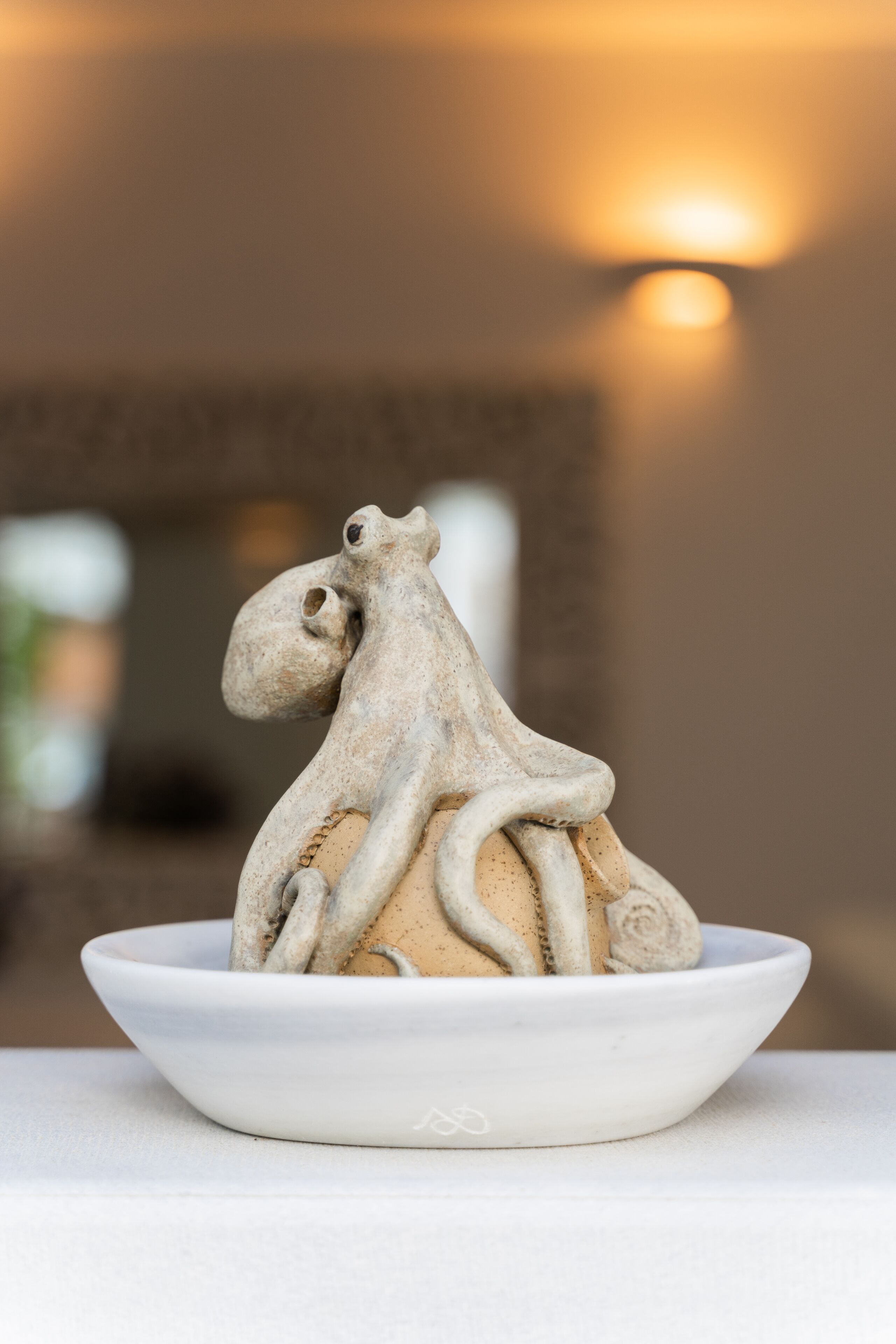 A ceramic sculpture of a horse and rider in a white bowl on a table.