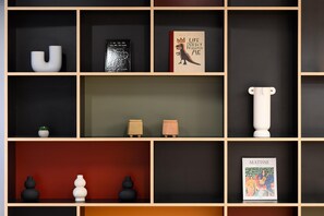 Une bibliothèque agrémentée de divers objets décoratifs, notamment des livres, des vases et des sculptures.