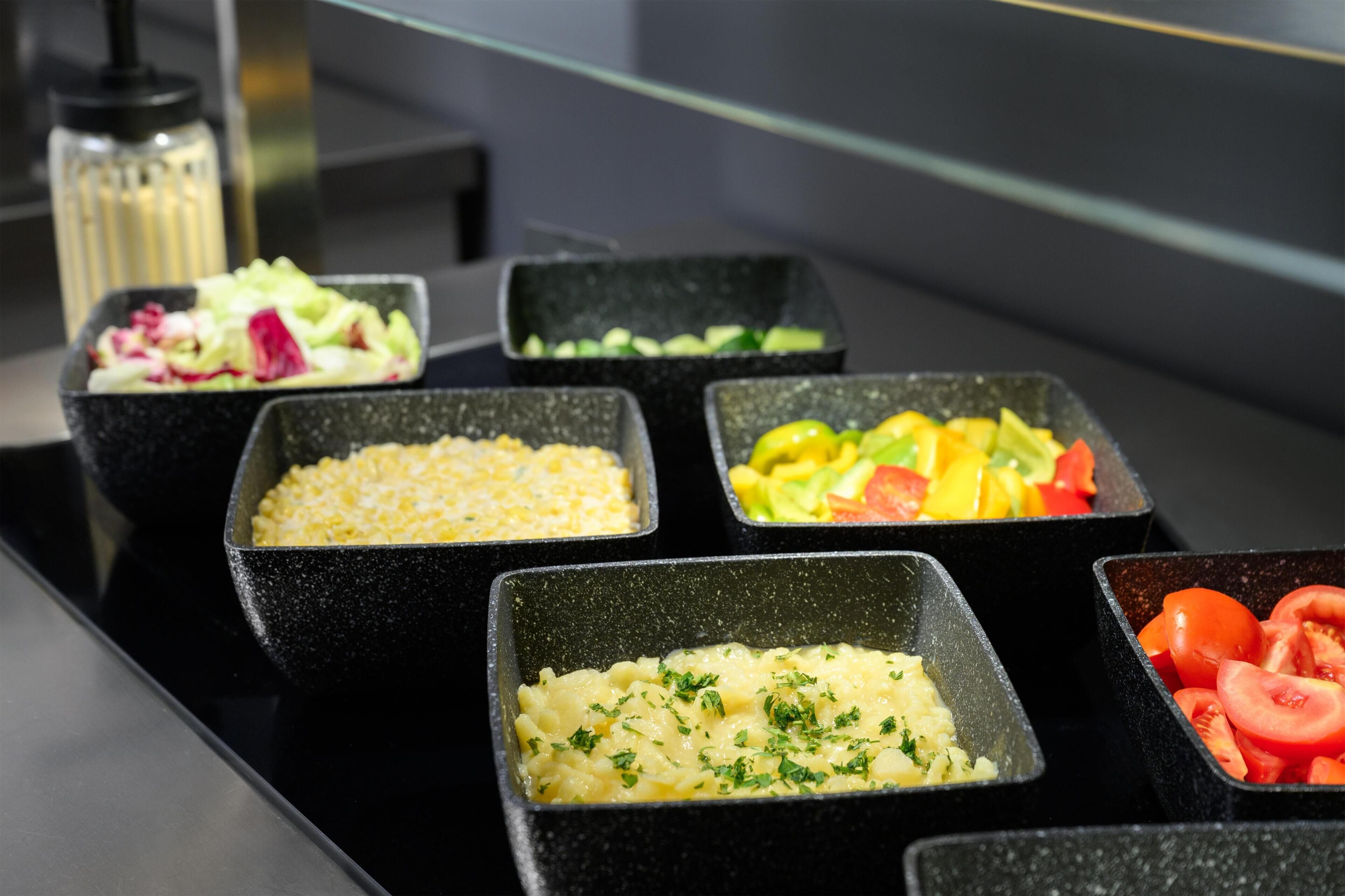 A buffet with various food options including salads, potatoes, and tomatoes.
