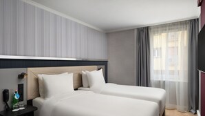 A hotel room with two beds, a bedside table with a phone and a bottle, and a window with curtains. - Hotel Erzsébet City Center Budapest, a member of Radisson Individuals (Budapest)