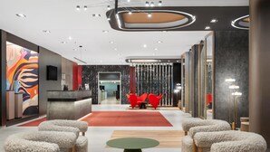 A modern hotel lobby with a reception desk, seating area, and decorative lighting.
