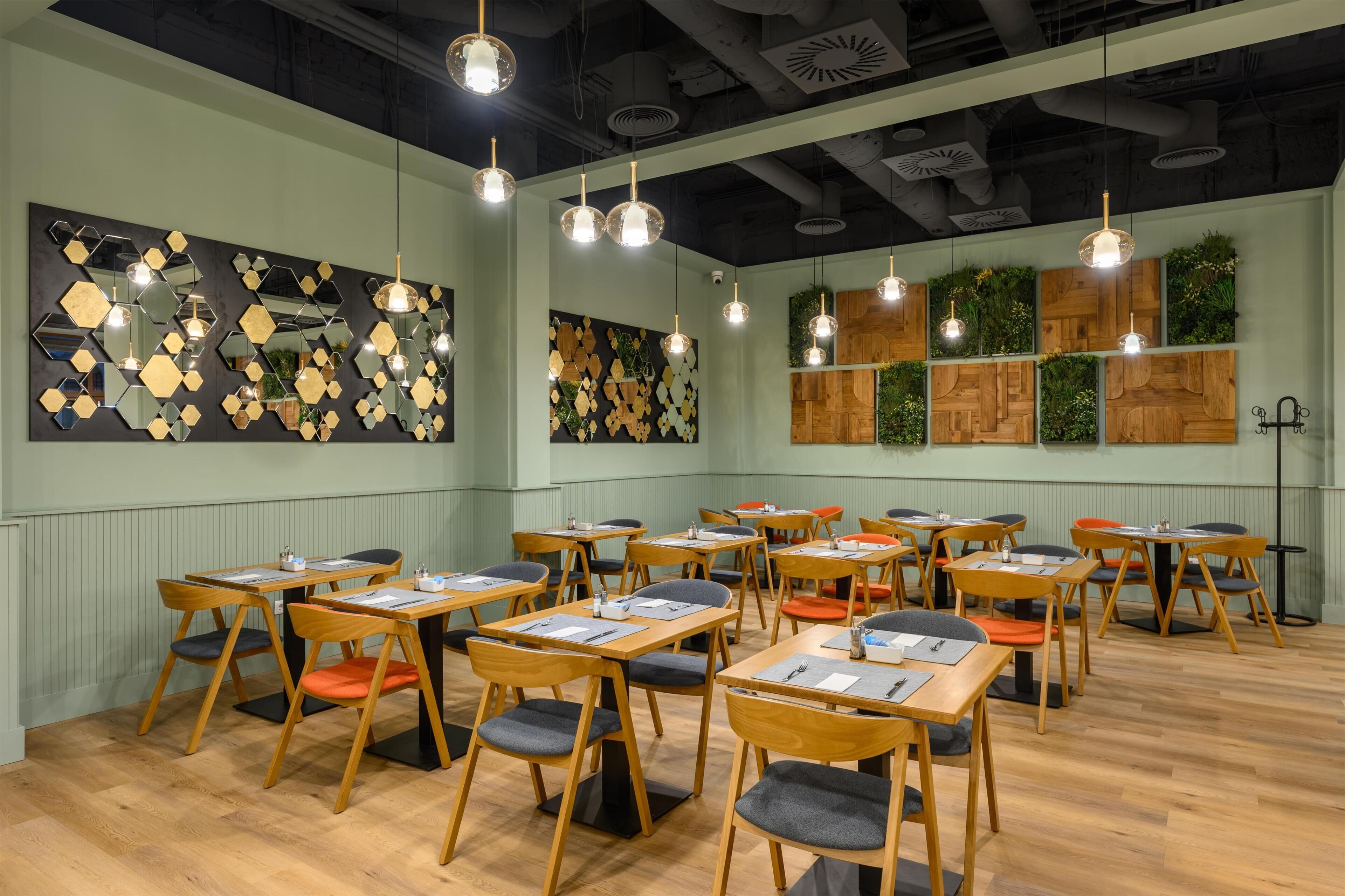 Sala de conferências com várias mesas e cadeiras, arte decorativa nas paredes e iluminação pendente.