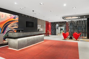 Un área de recepción moderna con mostrador, televisor de pantalla plana y alfombra roja.