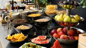 Buffet amb diverses opcions gastronòmiques, incloent fruita, pastissos i cereals.