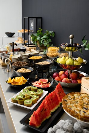 Un bufé con diversos alimentos, como frutas, pasteles y cereales.
