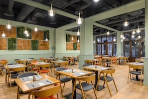 A spacious dining area with multiple tables and chairs, wooden panel walls, and hanging pendant lights. - Hotel Erzsébet City Center Budapest, a member of Radisson Individuals (Budapest)