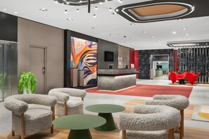 A modern lobby with a reception desk, plush chairs, and a large abstract mural.