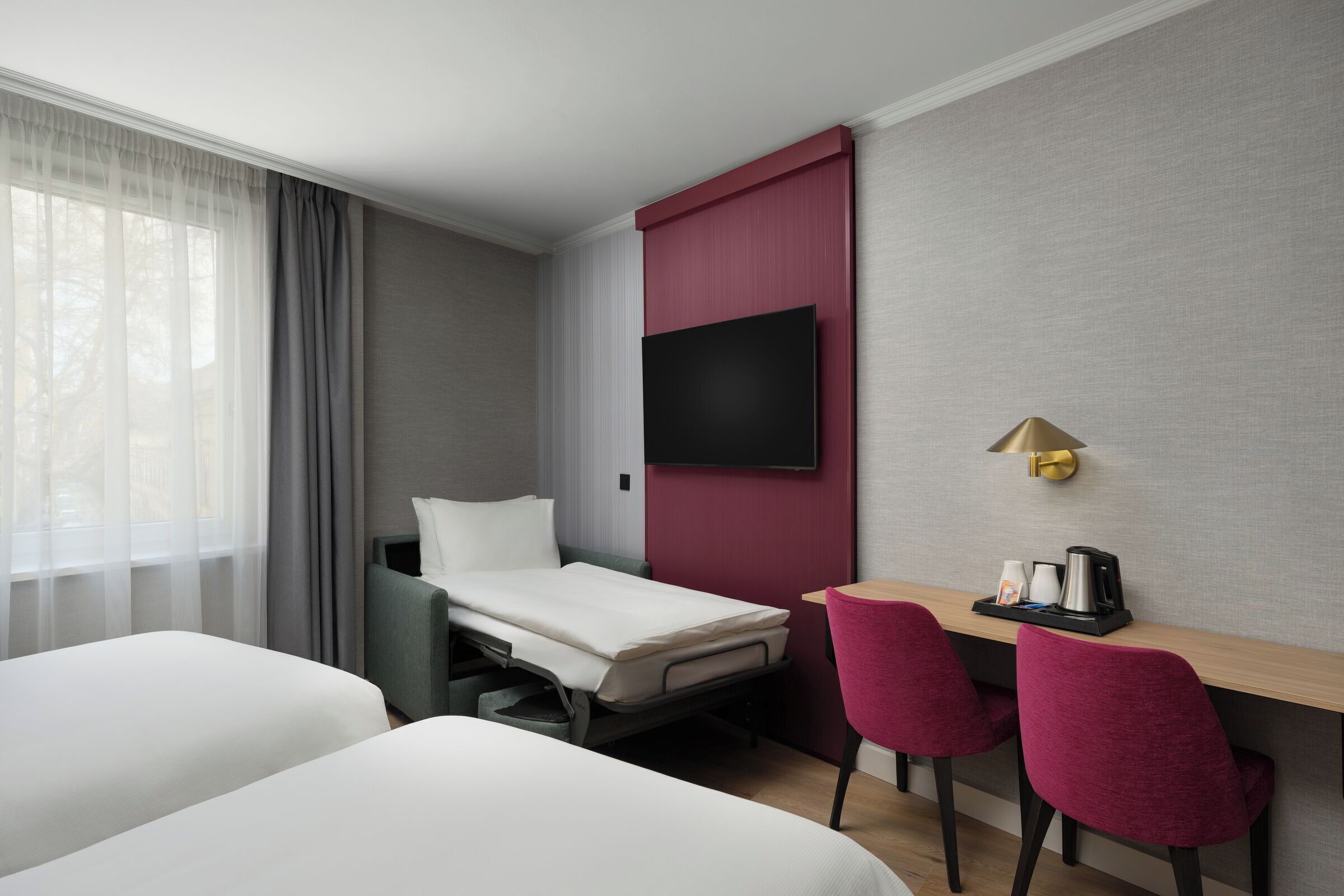 A hotel room with a bed, a desk with two chairs, a television, and a coffee maker.