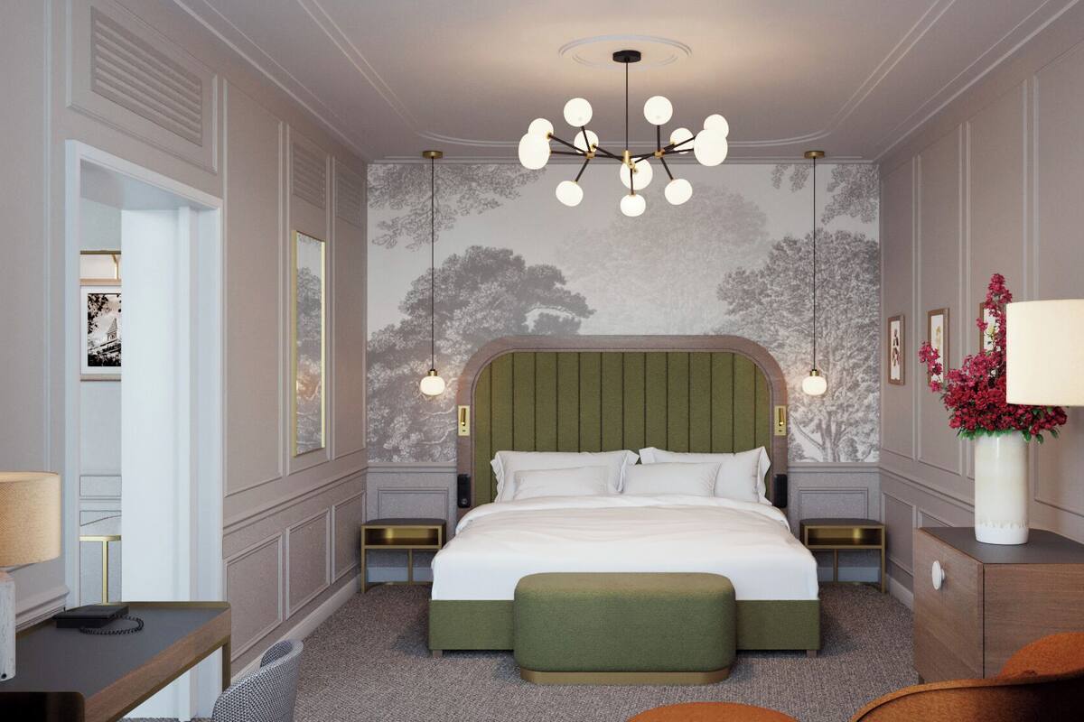 A bedroom with a large bed, a green upholstered bench, a desk with a lamp, and a wall-mounted chandelier.