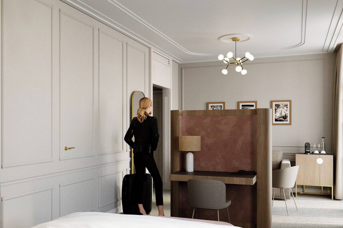 A hotel room with a large bed, a desk with a chair, a mirror, and a ceiling light fixture.