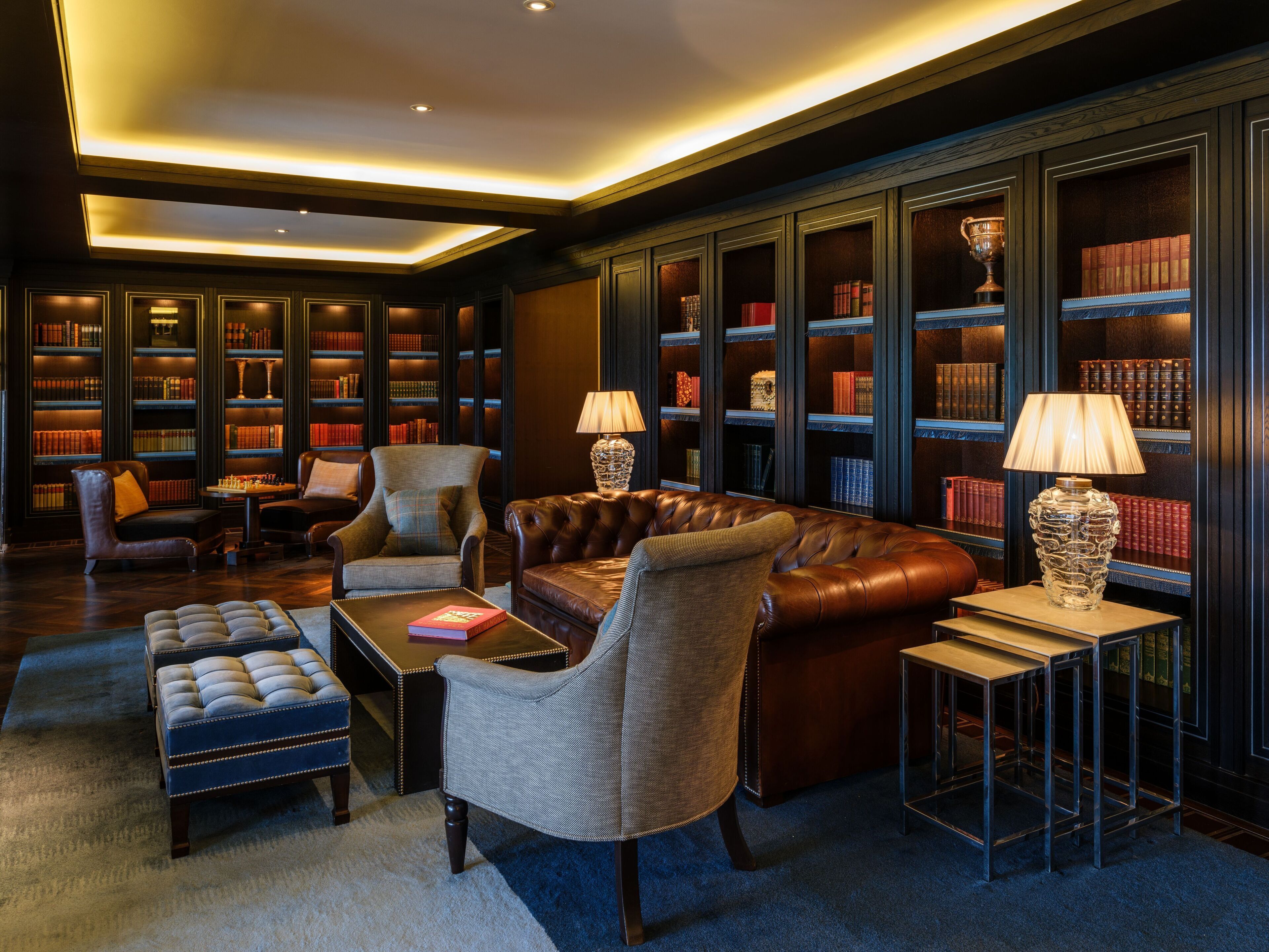 A library with leather sofas, bookshelves, and a chess table.