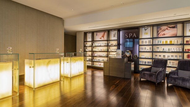 A modern spa reception area with a wooden floor, glass display cases, and a seating area with plush chairs. - The Europe Hotel & Resort (Killarney)